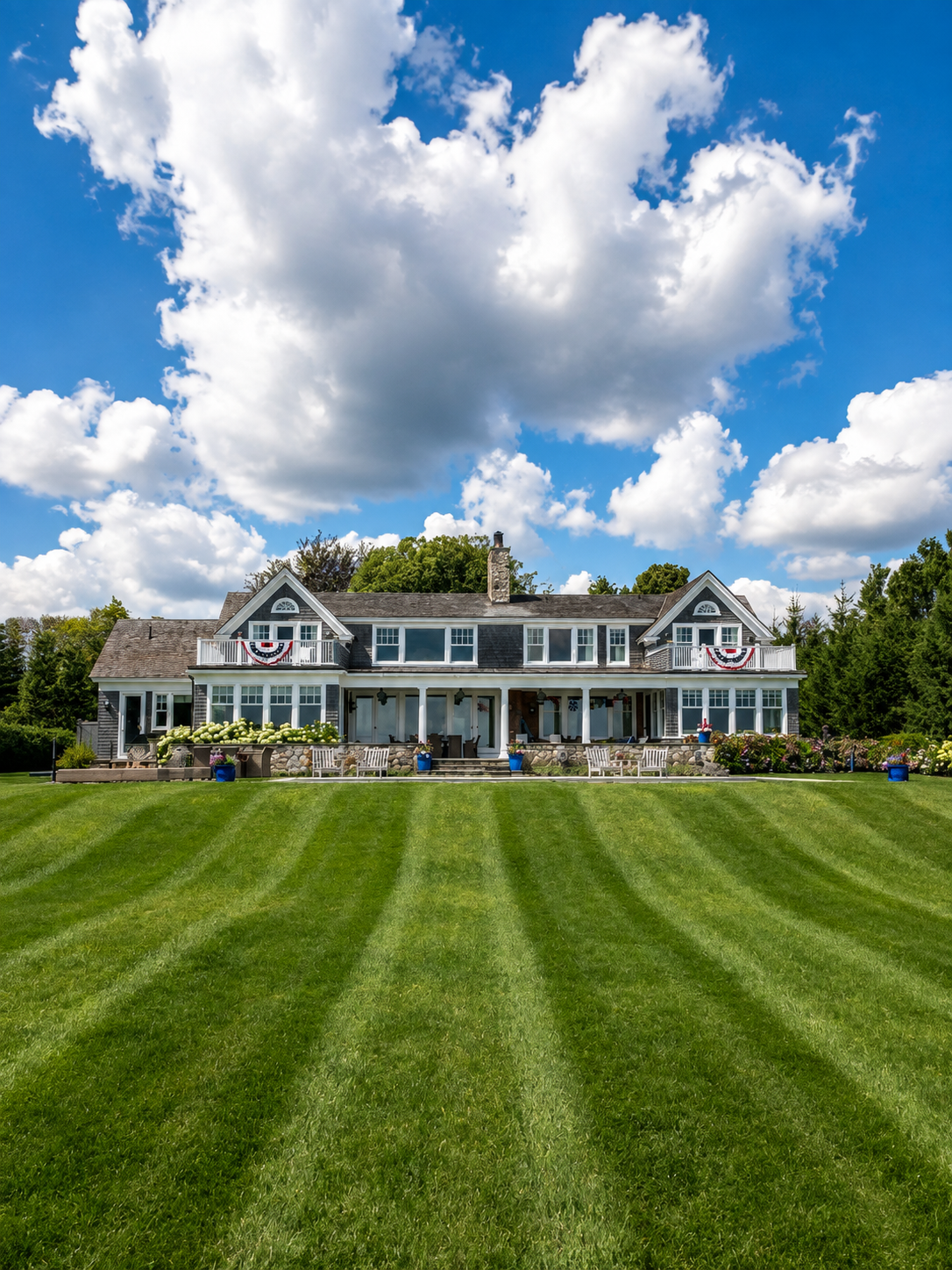 Technician cleaning windows of a large Nantucket-style estate with a water-fed pole